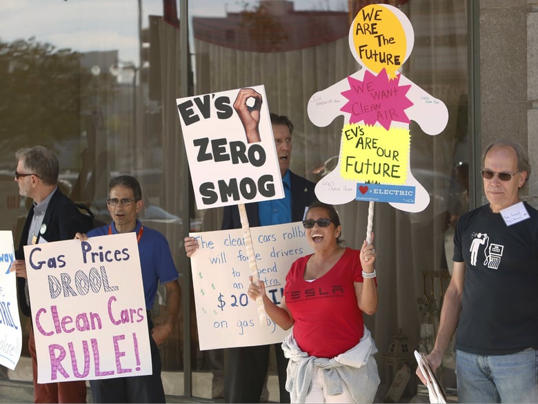 Linda Dunn, center, and Ron Freund, right, protest before the first of three public hearings on the Trump administration's proposal to roll back car-mileage standards in a region with some of the nation's worst air pollution Monday, Sept. 24, 2018.