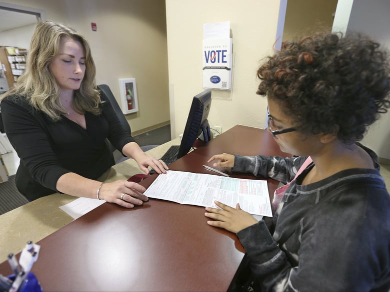 Sabine Kamagou, 19, right, gets help filling out voter registration form from Sacramento County Registrar of Voters employee, Cyndi Morrison, in Sacramento, Calif.