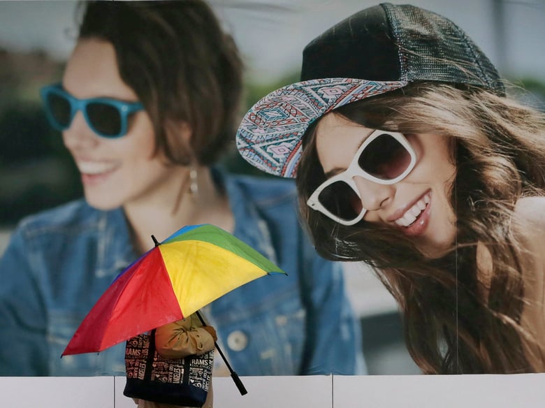 A pedestrian carries an umbrella as they stroll past an advertisment as a rainstorm moves through Sacramento, Calif., Wednesday, Feb. 13, 2019. Rain is falling widely in Northern California and is expected to spread south.