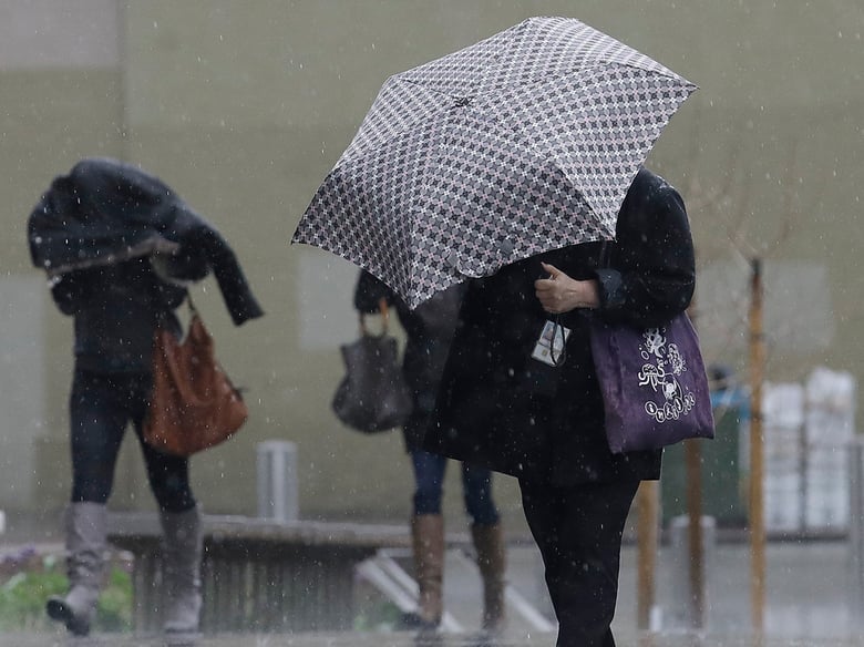 Women walk in the rain toward a federal court building in San Francisco, Monday, Feb. 25, 2019.