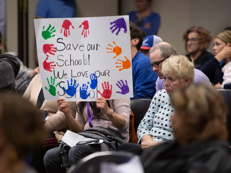 Audience members hold up signs at the Sacramento City Unified School District board meeting on April 4.