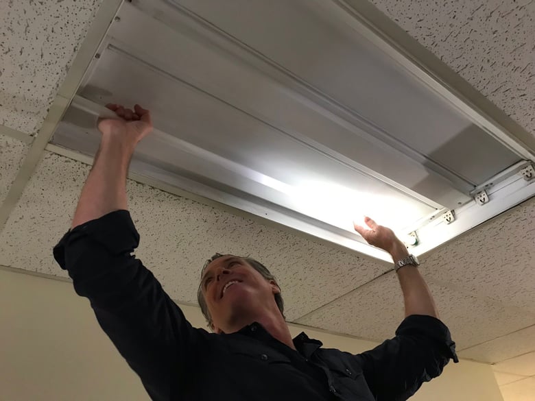 Gov. Gavin Newsom changes a light bulb on May Day at American River College in Sacramento.