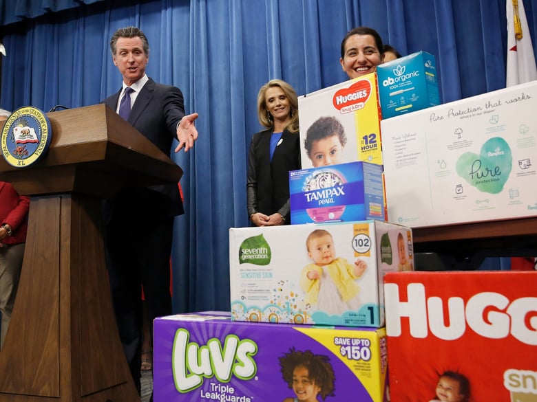 Gov. Gavin Newsom gestures towards boxes of tampons and diapers after proposing to eliminate from the state sales tax on such products in his upcoming state budget during a news conference, Tuesday, May 7, 2019.