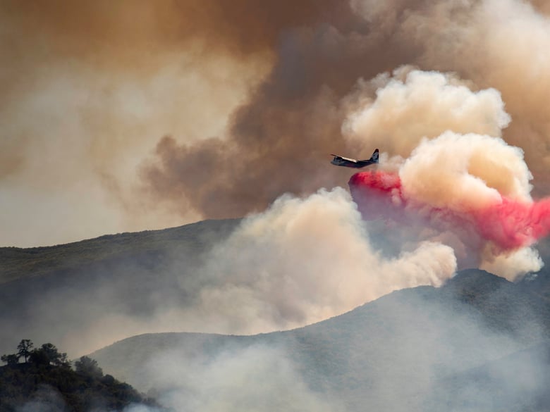 A plane drops fire retardant on a hillside in an attempt to box in flames from a wildfire during the Sand Fire in Rumsey, Calif., Sunday, June 9, 2019.