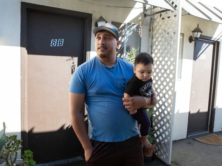 Alex Espinoza stands outside of his unit at Canal Farm Gardens with his 10-month-old son. He's been renting this apartment for more than five years, but following an eviction notice, will be forced to leave.