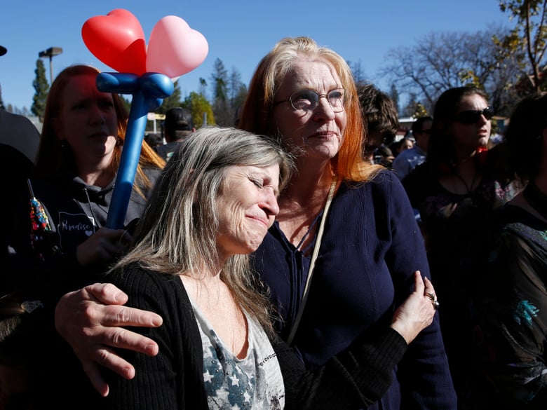 Tami Neves, left, is comforted by her sister, Orah Jones, right, during ceremonies for the one year anniversary of the Camp Fire, held in Paradise, Calif., Friday, Nov. 8, 2019.
