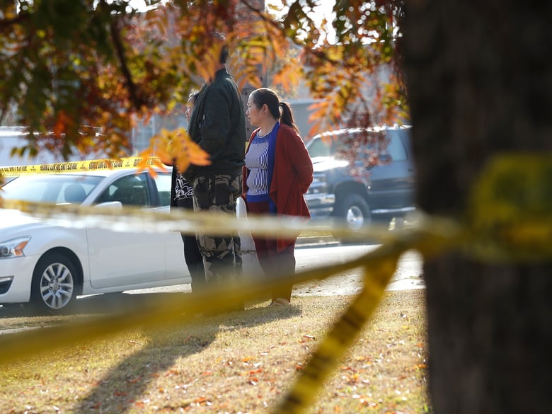 Yia Lee watches police investigate her neighbor's house on Lamona Ave. where a shooting took place at a house party which involved multiple fatalities and injuries in Fresno, Calif., Monday, Nov. 18, 2019.