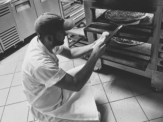 Ben Roberts prepares to take a pizza out of the oven at Pizza Supreme Being in Sacramento.