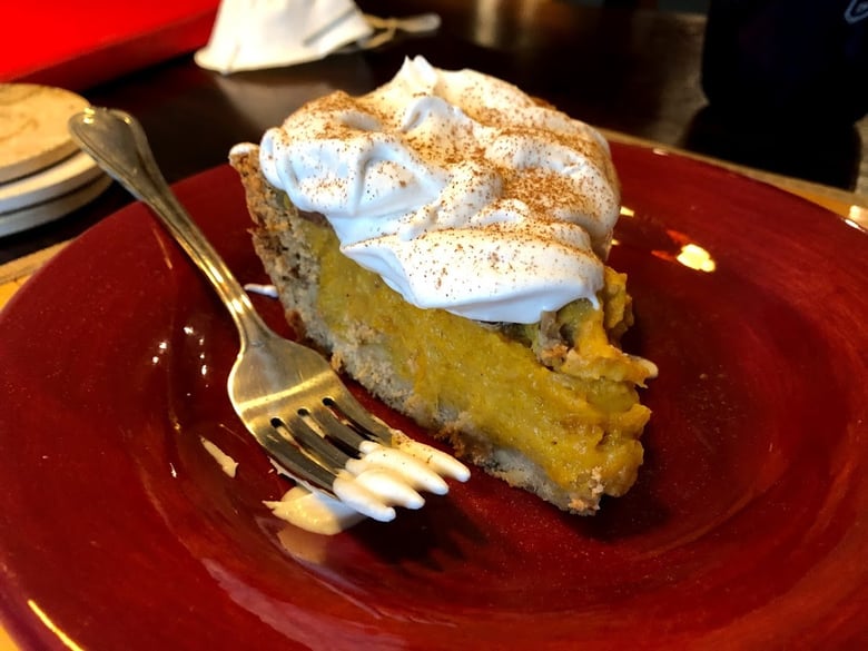 Homemade pumpkin pie with a face mask in the background.