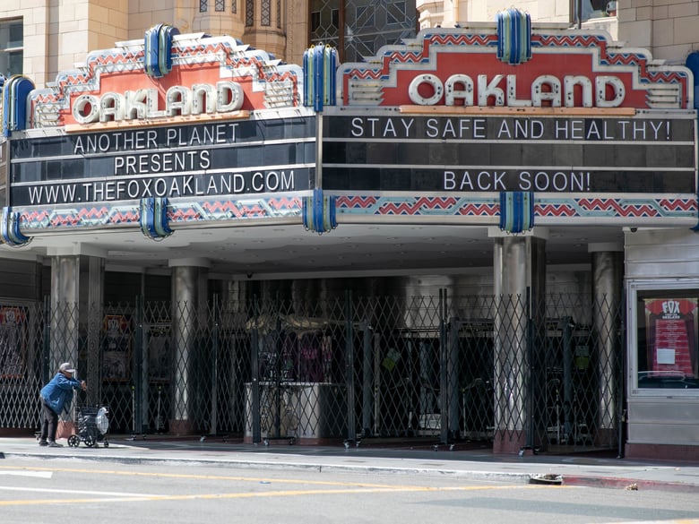 A woman pushes a cart past the shuttered Fox Theater in downtown Oakland on March 25, 2020.