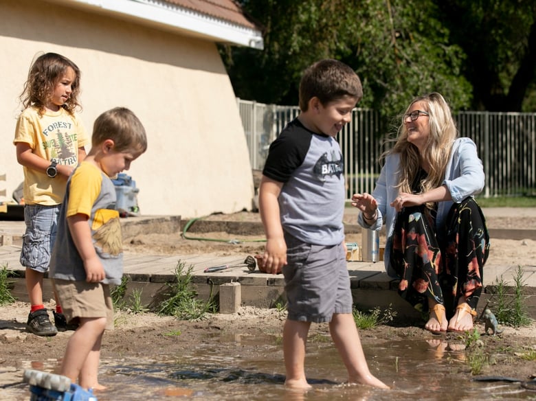 Amanda Simoni, owner of Heritage School of Discovery in Oakdale, laughs while students play in the school yard mud pit. A new California child care website aims to connect essential workers with available options.