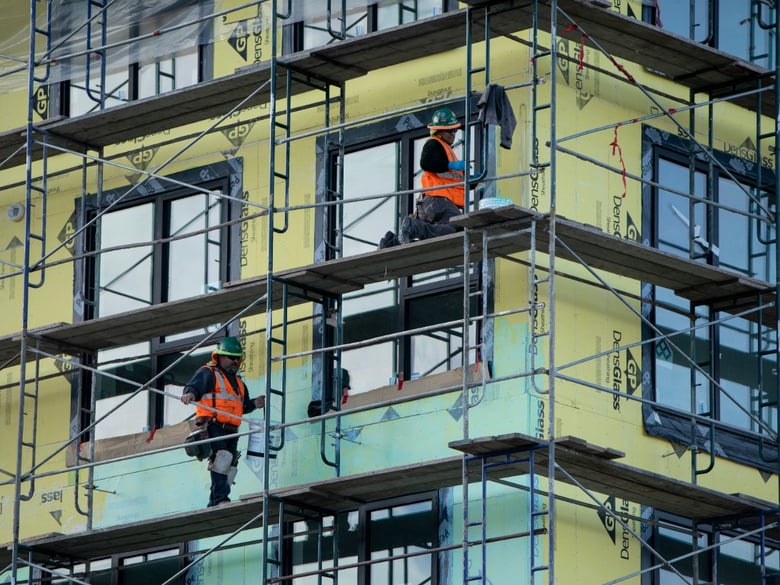 Workers paint a wall on a Factory OS construction project in West Oakland.
