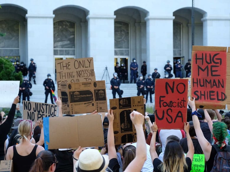 Demonstrators kneel at the east steps of the state Capitol. The crowd called for law enforcement officers on the steps to take a knee, but officers did not.