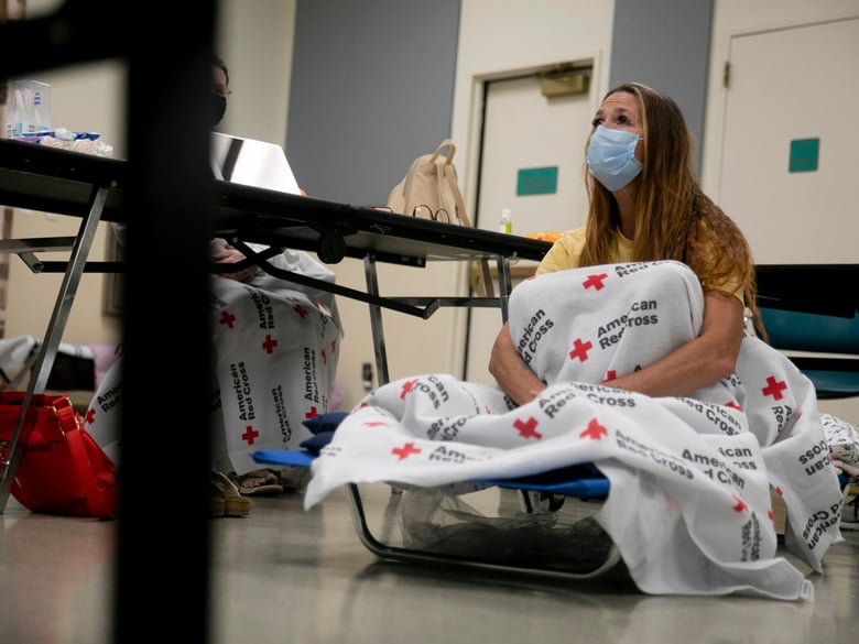Shawnee Whaley, 57, wears a mask as she rests on a cot at the Ulatis Community Center in Vacaville after evacuating her home on August 18, 2020.
