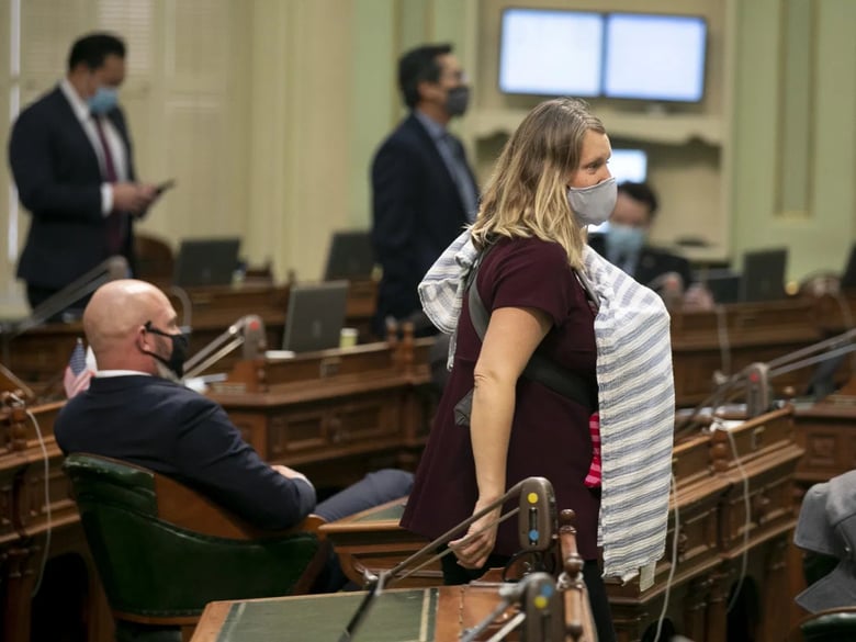 Assemblymember Buffy Wicks walks across the floor during a vote carrying her 1-month-old baby on Aug. 31, 2020. Wicks was not permitted to vote remotely despite having a newborn.