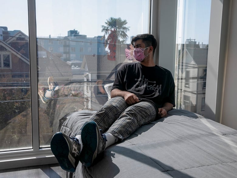 Isael Corona, a math major at UC Berkeley, looks out the window from his student apartment near campus where he lives with a roommate on Sept. 3, 2020. Corona says he misses being with his friends but wanted to be back on campus.