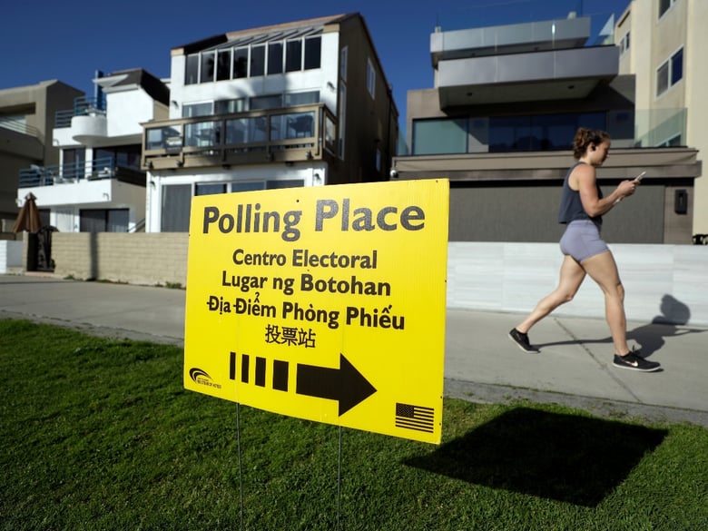 In this March 3, 2020 file photo, a woman runs on a path by a polling place during primary elections in San Diego.