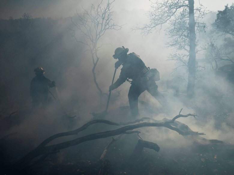 A firefighter extinguishes hotspots while battling the Olinda Fire in Anderson, Calif., Sunday, Oct. 25, 2020. The blaze was one of four fires burning near Redding that firefighters scrambled to stop as high winds buffeted Northern California.