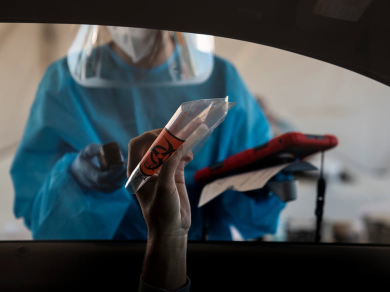 A driver holds up his nasal swab sample while talking to a medical assistant at a COVID-19 testing site set up at the OC Fairgrounds in Costa Mesa, Calif., Monday, Nov. 16, 2020.