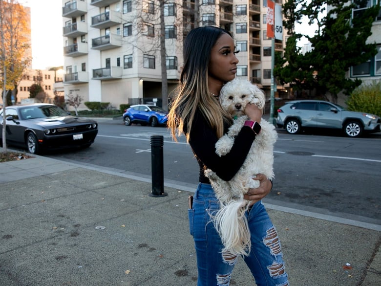 Jhonae Mazique carries her dog, Simba, to her friend’s apartment where she’s currently staying after losing her housing earlier this year, in Oakland on Dec. 8, 2020.