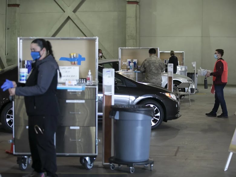 National Guard members and medical personnel administer COVID vaccines to health care workers at a drive-through distribution site at Cal Expo in Sacramento on Jan. 21, 2021.