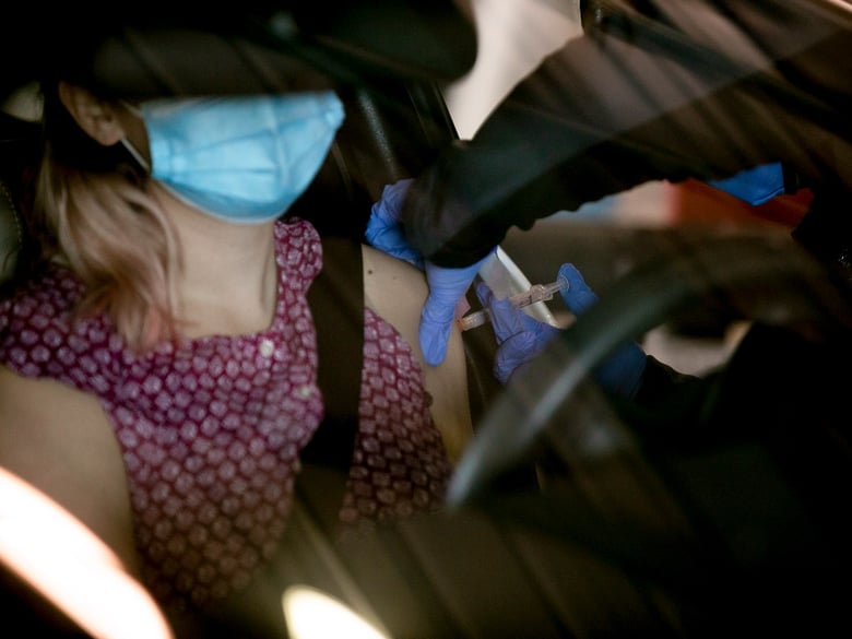 Health care workers receive COVID vaccinations at a drive-through distribution site at Cal Expo in Sacramento on Jan. 21, 2021.