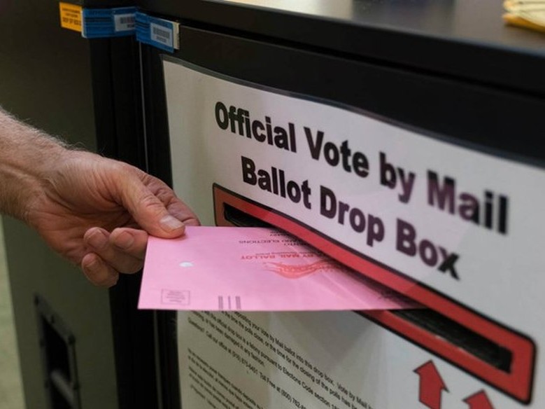 A voter returns a vote by mail ballot in California.