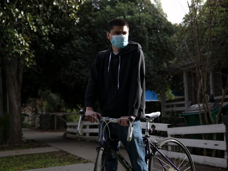 CSU Chico junior Julian Mendoza stands with his bike near where he was stopped by university police—nearly a dozen blocks away from campus—for riding his bike on campus, on Feb. 16, 2021.