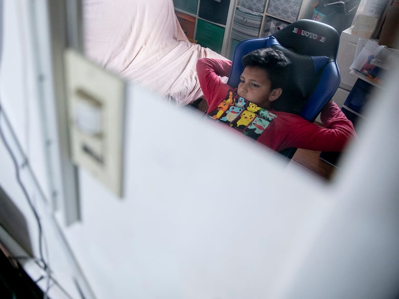 Mario Ramírez Garcia, 10, listen as his teacher addresses the class during distance learning in the bedroom he shares with his sister on April 23, 2021.