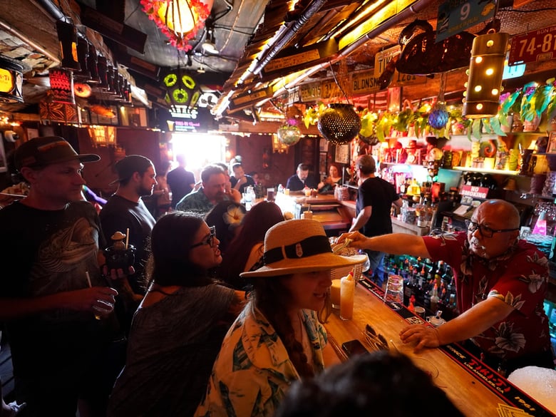 Maskless patrons enjoy tropical cocktails in the tiny interior of the Tiki-Ti bar as it reopens on Sunset Boulevard in Los Angeles on July 7, 2021. California COVID cases are climbing, especially in Los Angeles.