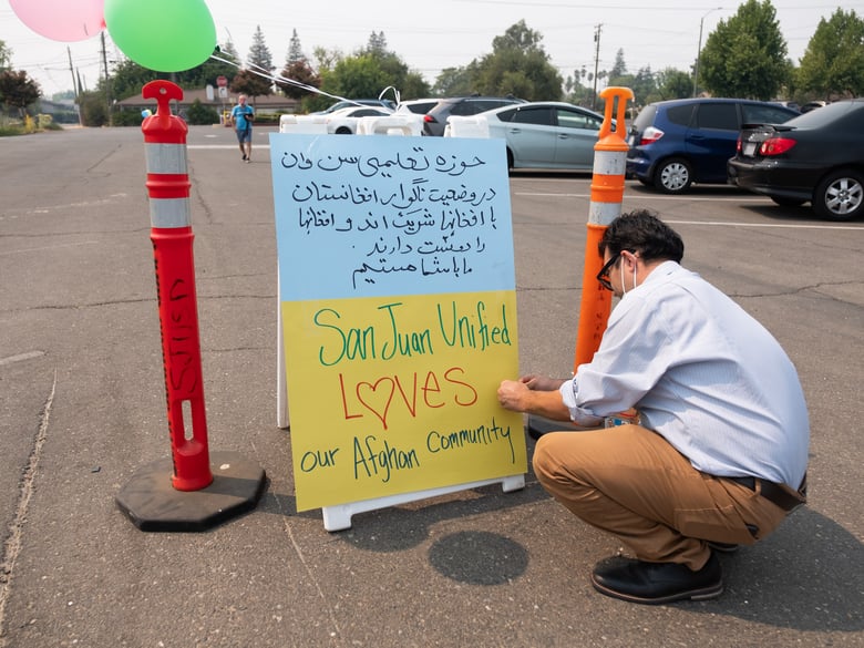 San Juan Unified School District employee Abdul Safay puts up signs at a food distribution and resource fair catering to Afghan families on Thursday Aug. 19, 2021 at Encina High School.