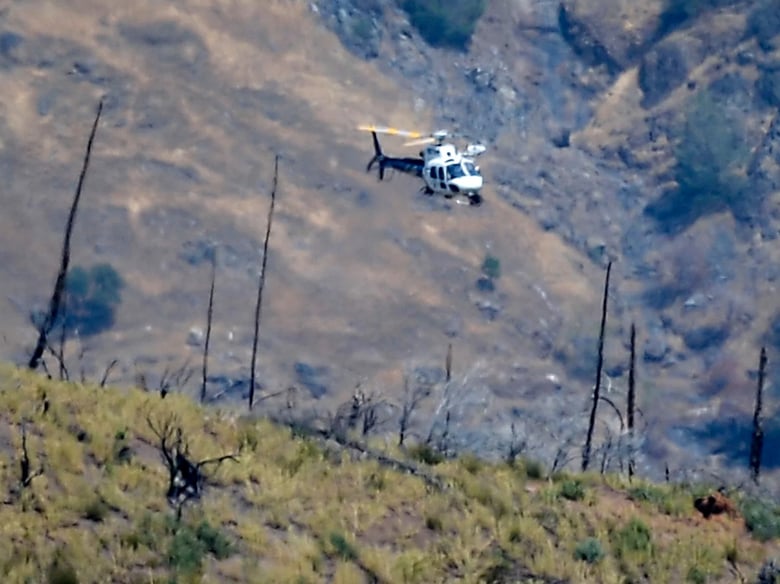 A helicopter hovers over a remote area northeast of the town of Mariposa, Calif., on Wednesday. According to the Mariposa County Sheriff's Office, the area is reported to be where a family and their dog were found dead on a hiking trail on Tuesday.