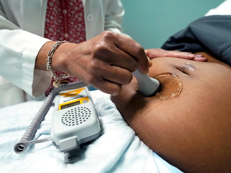 A doctor uses a hand-held Doppler probe on a pregnant woman to measure the heartbeat of the fetus on Dec. 17, 2021, in Jackson, Miss.