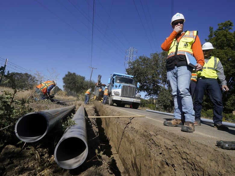 Paul Standen, senior director of underground regional delivery, second from right, and project manager Jeremy Schanaker, right, look on during a tour of a Pacific Gas & Electric crew burying power lines in Vacaville, Calif., Wednesday, Oct. 11, 2023.