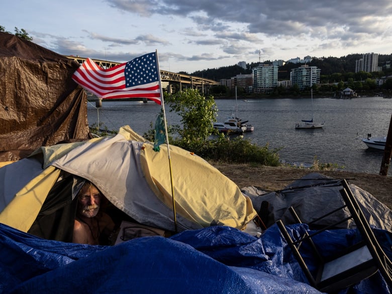 A man named Frank sits in his tent with a river view in Portland, Ore., in 2021. A lawsuit originally filed in 2018 on behalf of homeless people in the Oregon city of Grants Pass is set to go before the U.S. Supreme Court in April.