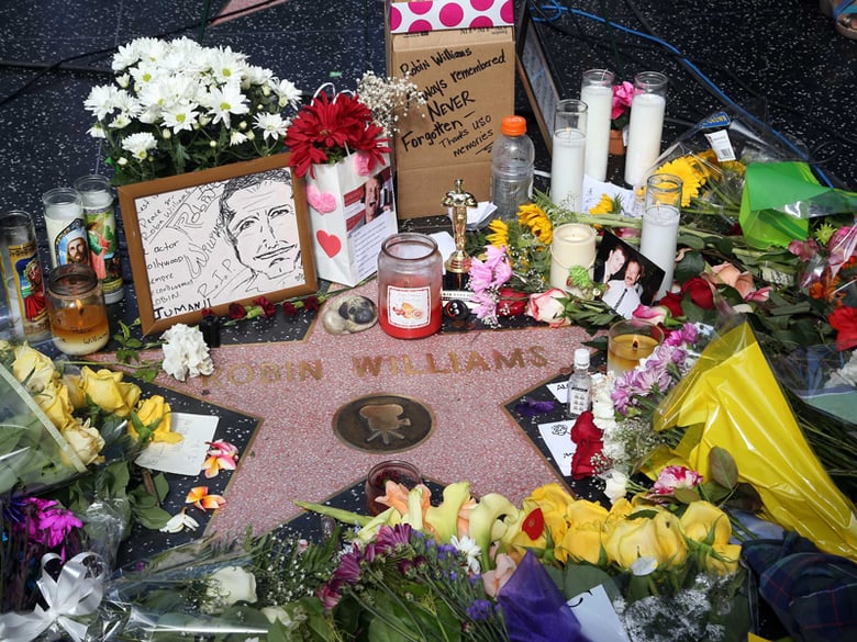 Flowers, photographs and candles surround the star of actor-comedian Robin Williams forming a makeshift memorial along the Hollywood Walk of Fame in Los Angeles on Tuesday, Aug. 12, 2014. Williams, 63, died at his San Francisco Bay Area home.