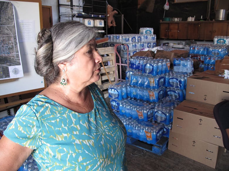 In this Monday, Sept. 15, 2014 photo, Elva Beltran, director of the Porterville Area Coordinating Council, is shown in the charity’s warehouse filled with donated water in Porterville, Calif. 