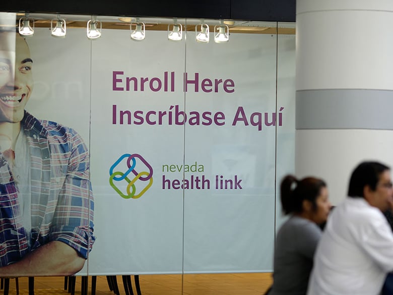 FILE - This Nov. 13, 2014 file photo people stand near an insurance store for Nevada Health Link at the Boulevard Mall in Las Vegas. 