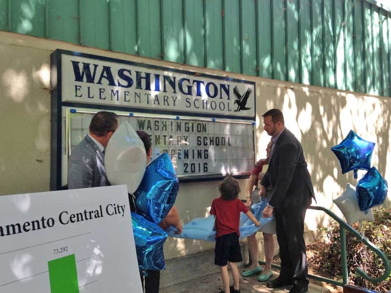 Superintendent Jose Banda and Councilman Steve Hansen unveil the Opening Fall 2016 sign with neighborhood kids at Washington Elementary.