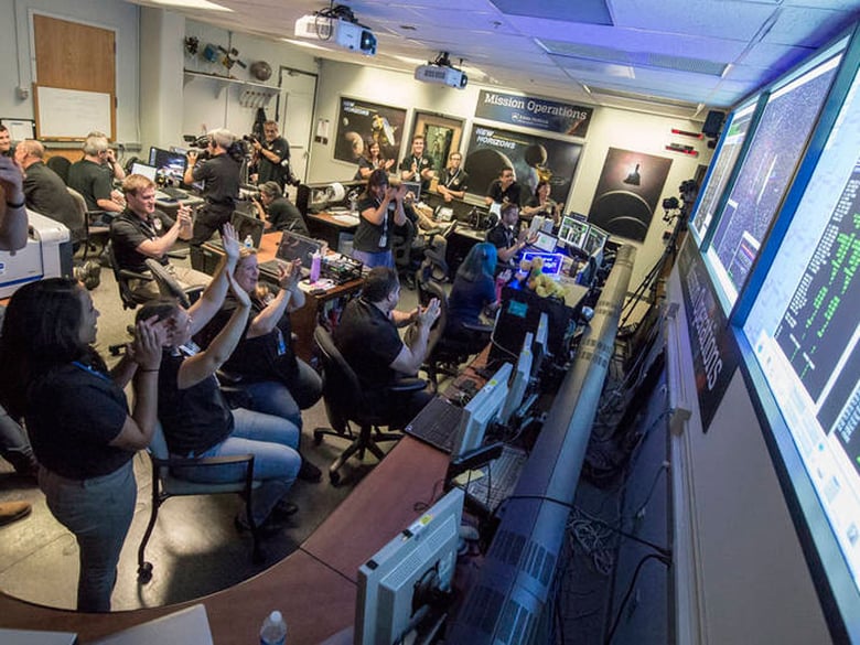 New Horizons Flight Controllers celebrate after they received confirmation from the spacecraft that it had successfully completed the flyby of Pluto, Tuesday, July 14, 2015.