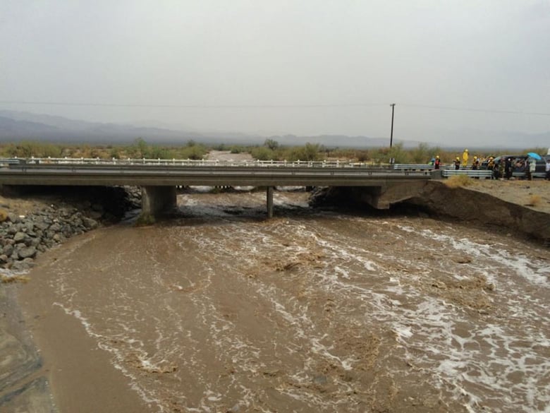 Waters rush under an the elevated portion westbound Interstate 10 as emergency crews respond to the collapse of the eastbound section, Sunday, July 19, 2015, in Desert Center, Calif.