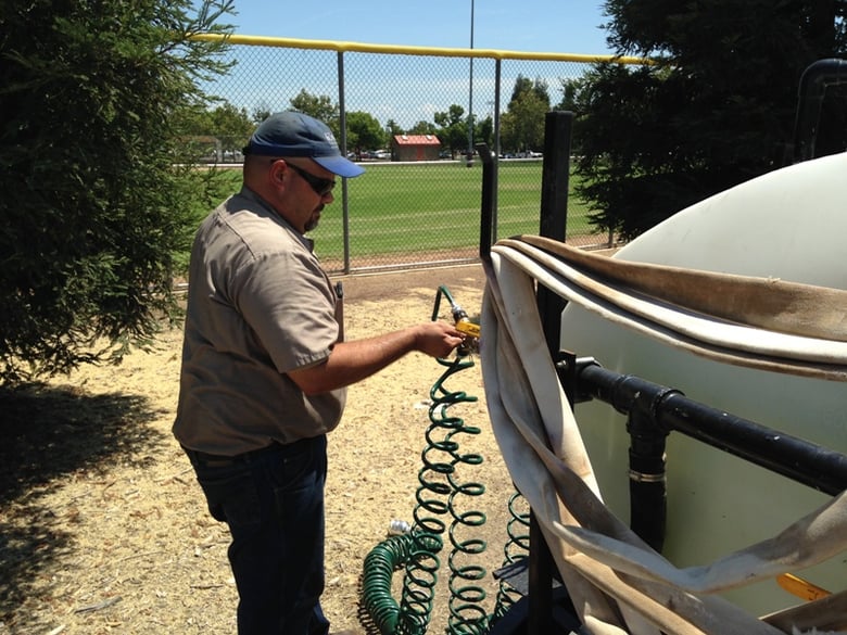 Steve Rhoden hooks up a hose to a tank of recycled water as he prepares to water some of the redwoods in the City of Roseville park system.