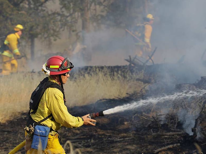 A firefighter sprays a hose toward a spot fire in the Rocky Fire burn area along Morgan Valley Road near Lower Lake, Calif., Friday, July 31, 2015. 