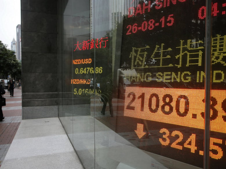A woman walks past an electronic board showing Hong Kong share index outside a local bank in Hong Kong, Wednesday, Aug. 26, 2015. 