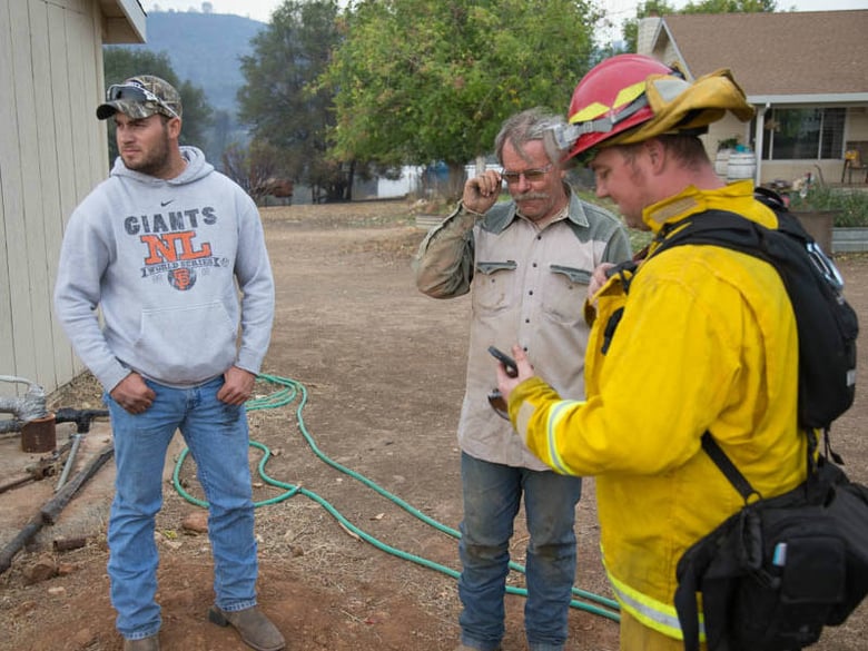 Mike Thomas and his father-in-law, Lonnie Thompson, ask a firefighter to help them get water for Thompson's cattle. They haven't had water in two days.