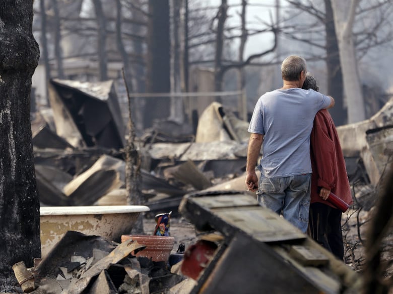 Richard and Kathie Reeves embrace as they stand in the remains of the home of close friends that was destroyed in a wildfire several days earlier, Tuesday, Sept. 15, 2015, in Middletown, Calif.