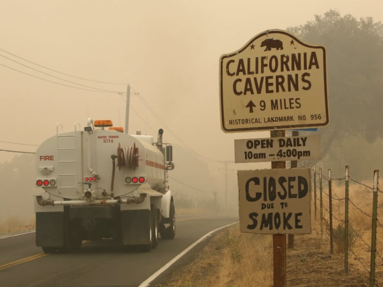 A water truck passes a warning sign that the California Caverns historic site is closed due to smoke from the Butte Fire, Saturday, Sept. 12, 2015, near San Andreas, Calif. 