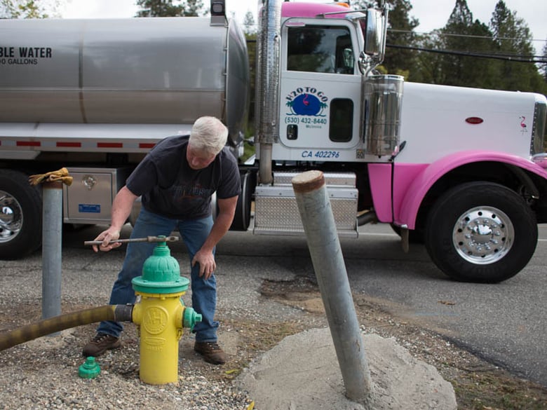 Garrett McInnis with "H2O to Go" water hauling taps hydrant to fill his tanker truck.
