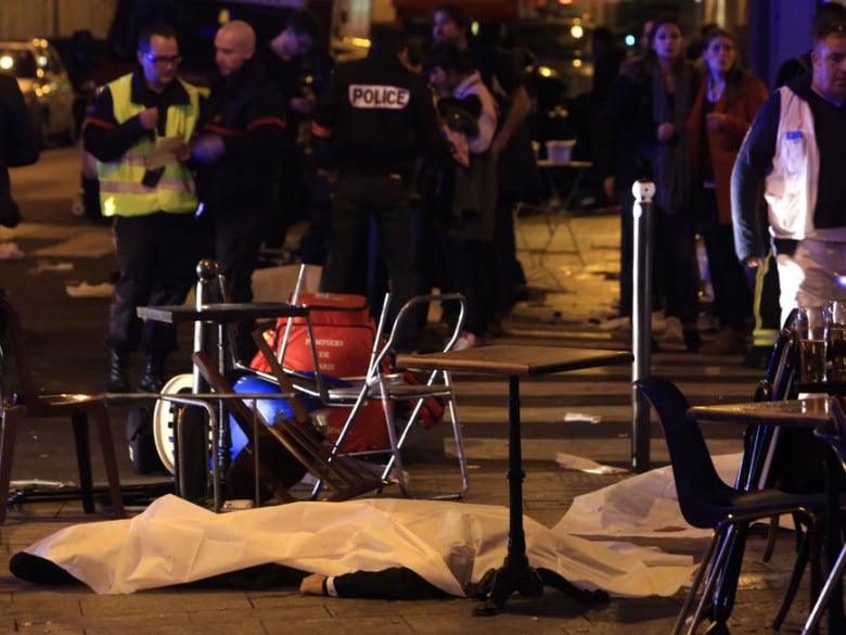 A victim is pictured on the pavement outside a Paris restaurant, Friday, Nov. 13, 2015. Two police officials say at least 11 people have been killed in shootouts and other violence around Paris. 