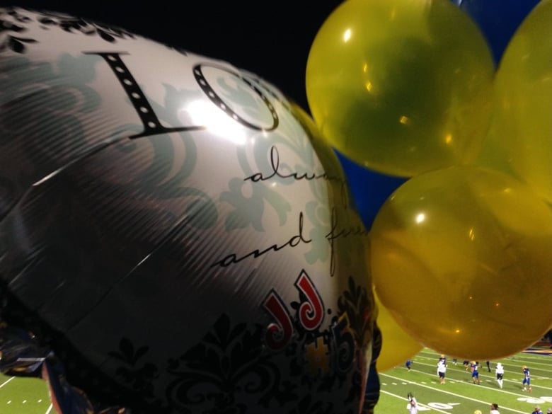 Balloons bearing JJ Clavo's name and football uniform number were released into the sky prior to Grant Union High School's playoff game Monday night. Clavo was killed and a teammate was injured by gunfire Friday. 